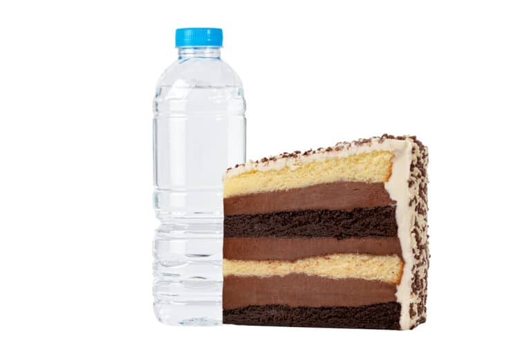 A slice of Black and White Fudge cake beside a water bottle
