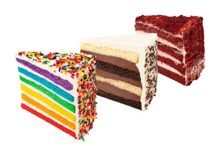 Three slices of cake next to each other: vanilla rainbow, black and white fudge, and red velvet.